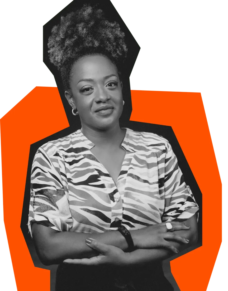 Instrutora da Mentaleria: Samita Vaz Imagem de Samita Vaz, instrutora da Mentaleria, com expressão serena e braços cruzados. Samita está usando uma blusa estampada de zebra, contra um fundo de cores vibrantes em laranja e roxo.